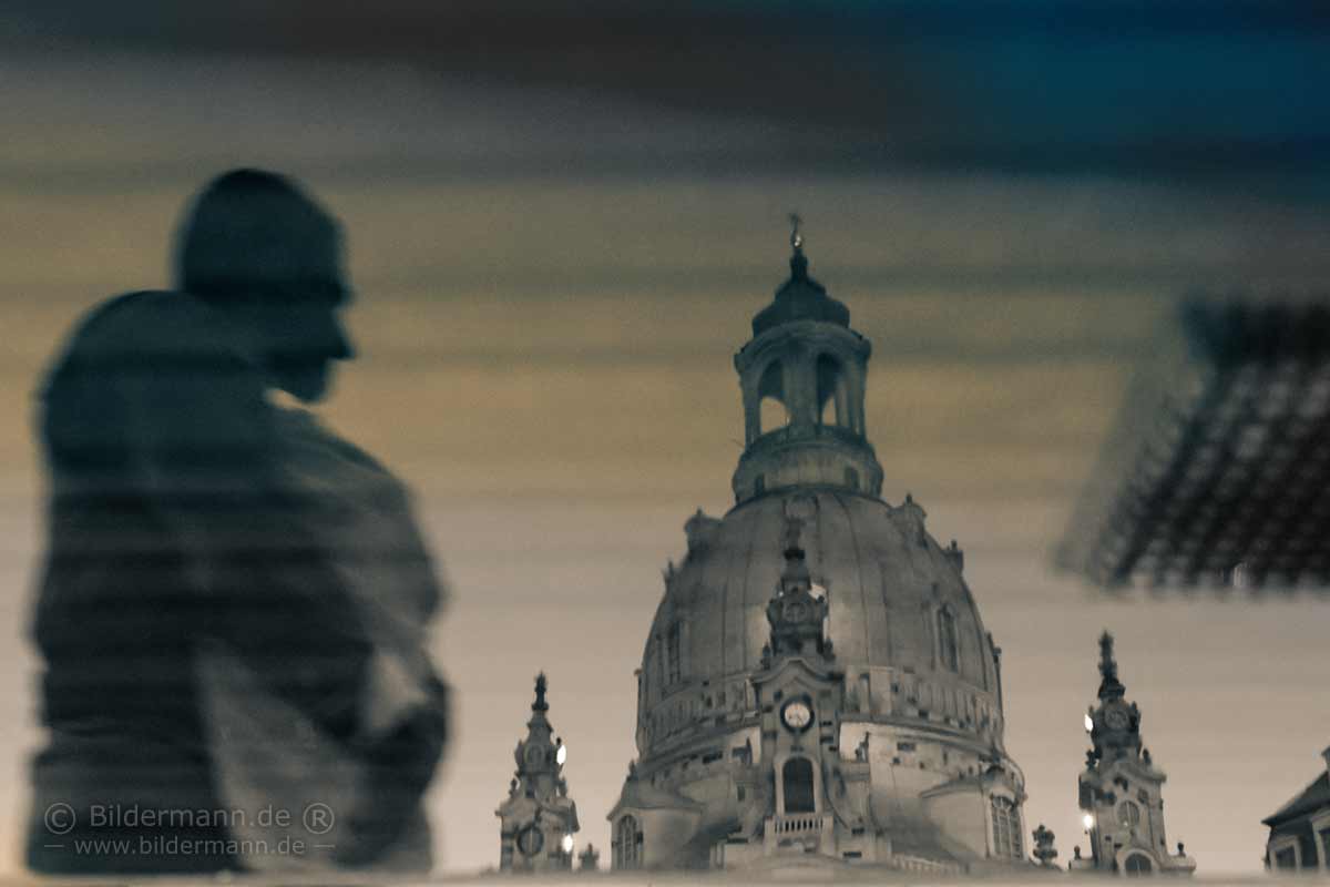 Spieglung der Frauenkirche Dresden in einer Pfütze bei Dämmerung.