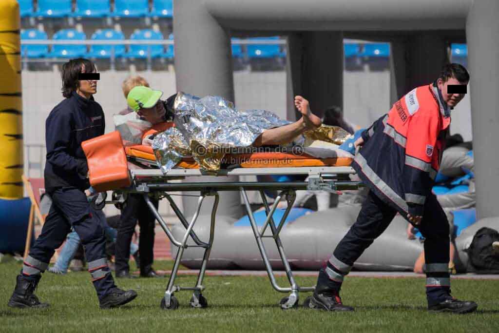 Foto Rubrik Fotografie Zitate: Ein verletzter Marathoni wird von Rettungssanitaetern abtransportiert.
